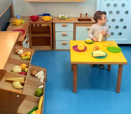 Nella sez piccoli è presente un angolo dedicato al gioco simbolico rappresentato da una cucina dove i bambini hanno a disposizione cibo, piatti e pentole di plastica che permettono di interpretare la realtà  a loro piacimento.